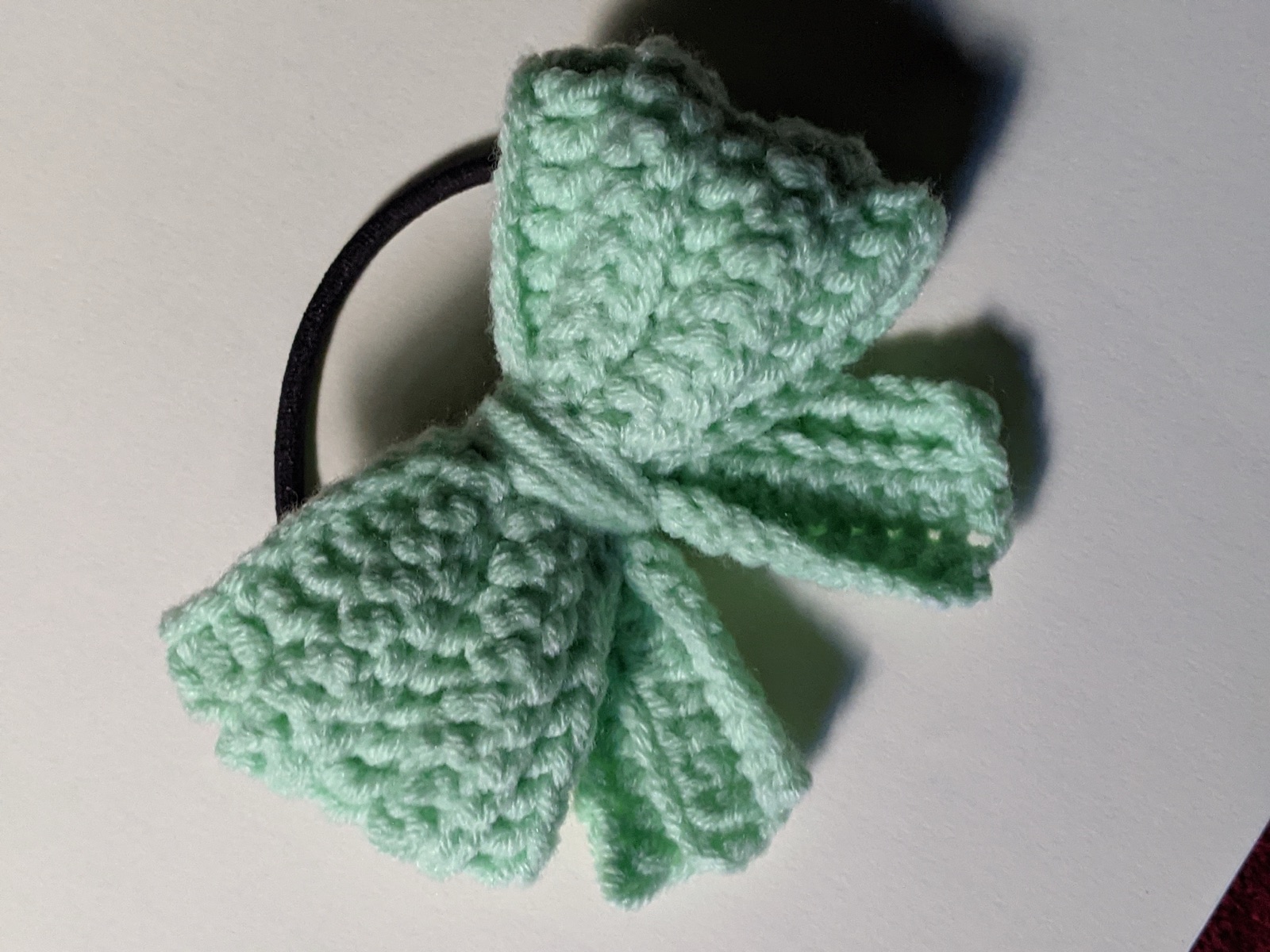 Top-down view of a finished mint green puffy crochet bow