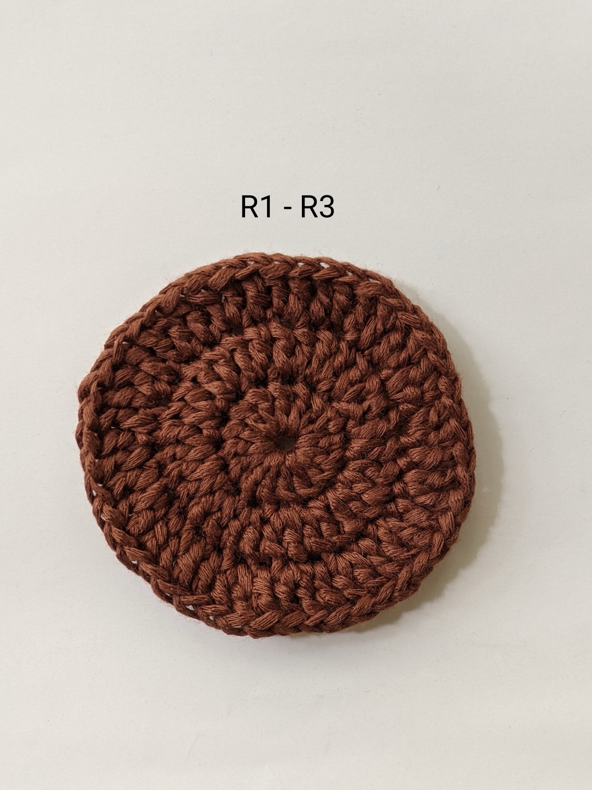 Finished dark brown crocheted center disc for a sunflower coaster after rounds 1 to 3, showing 45 stitches in the outer round
