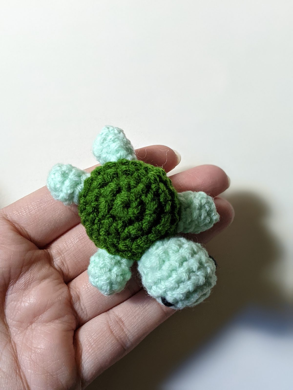 Finished mint and dark green tiny pocket turtle resting in an open palm to show palm-size scale