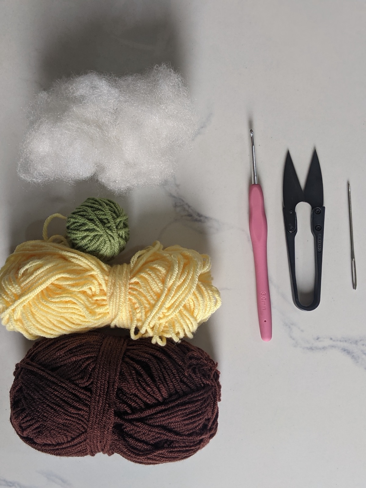Yellow, dark brown, and green milk cotton yarn with a 3 mm hook, scissors, a tapestry needle, and fiberfill stuffing