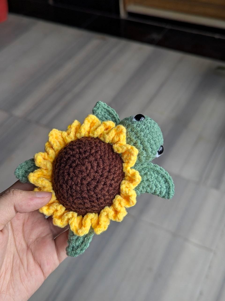 Side view of the finished crochet sunflower turtle showing the petal ring and green flippers
