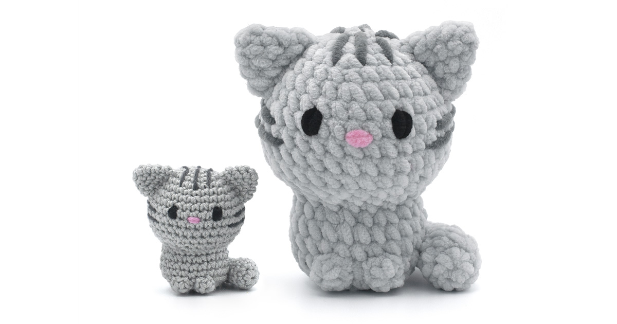 Two grey crocheted tabby cats side by side, a small sport-weight version and a large chenille version, on a white background