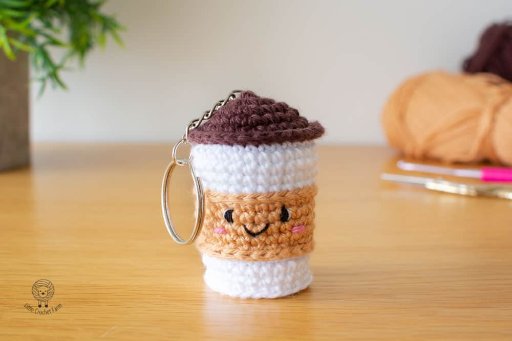 A small crochet takeaway coffee cup keychain in brown and white, by Little Crochet Farm
