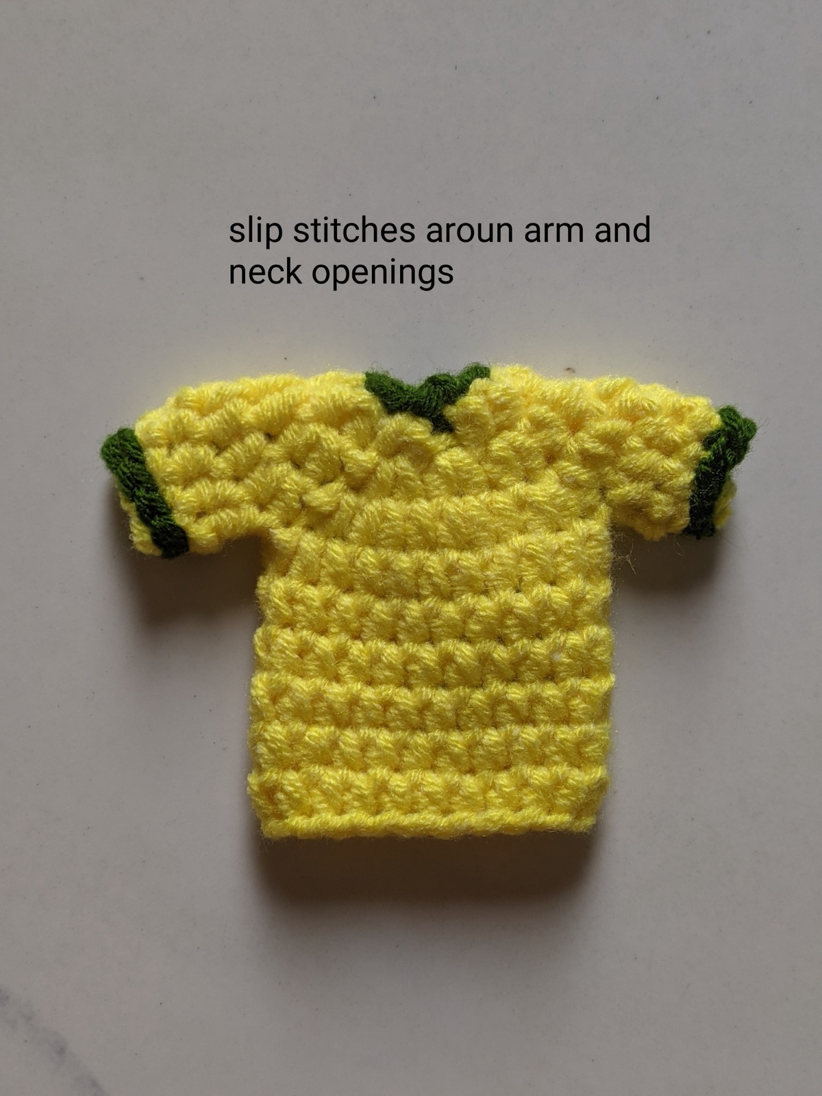 The yellow crochet jersey with dark green slip stitches worked around the neckline and both sleeve cuffs
