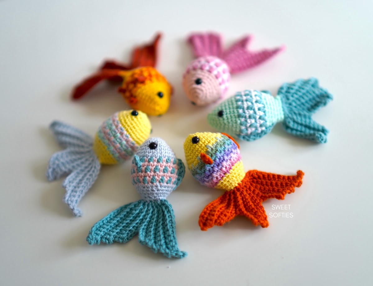 Six small crochet goldfish in different colors with textured scale patterns and fanned tails